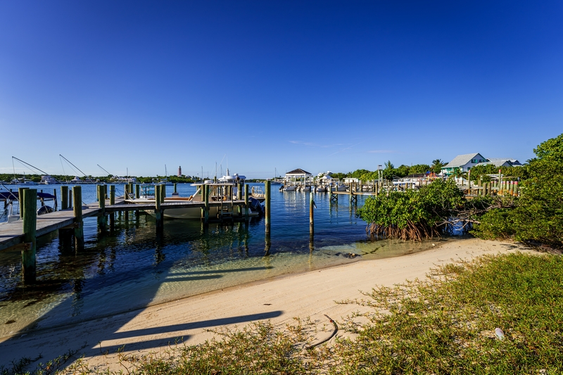 Busy dock with motorboats and nearby beach cottages in Elbow Cay., Bahamas